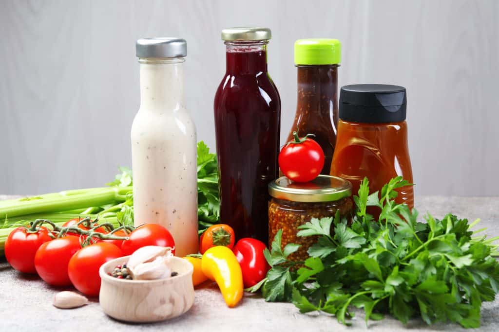 productos de ensalada junto con diferentes salsas que acompañan